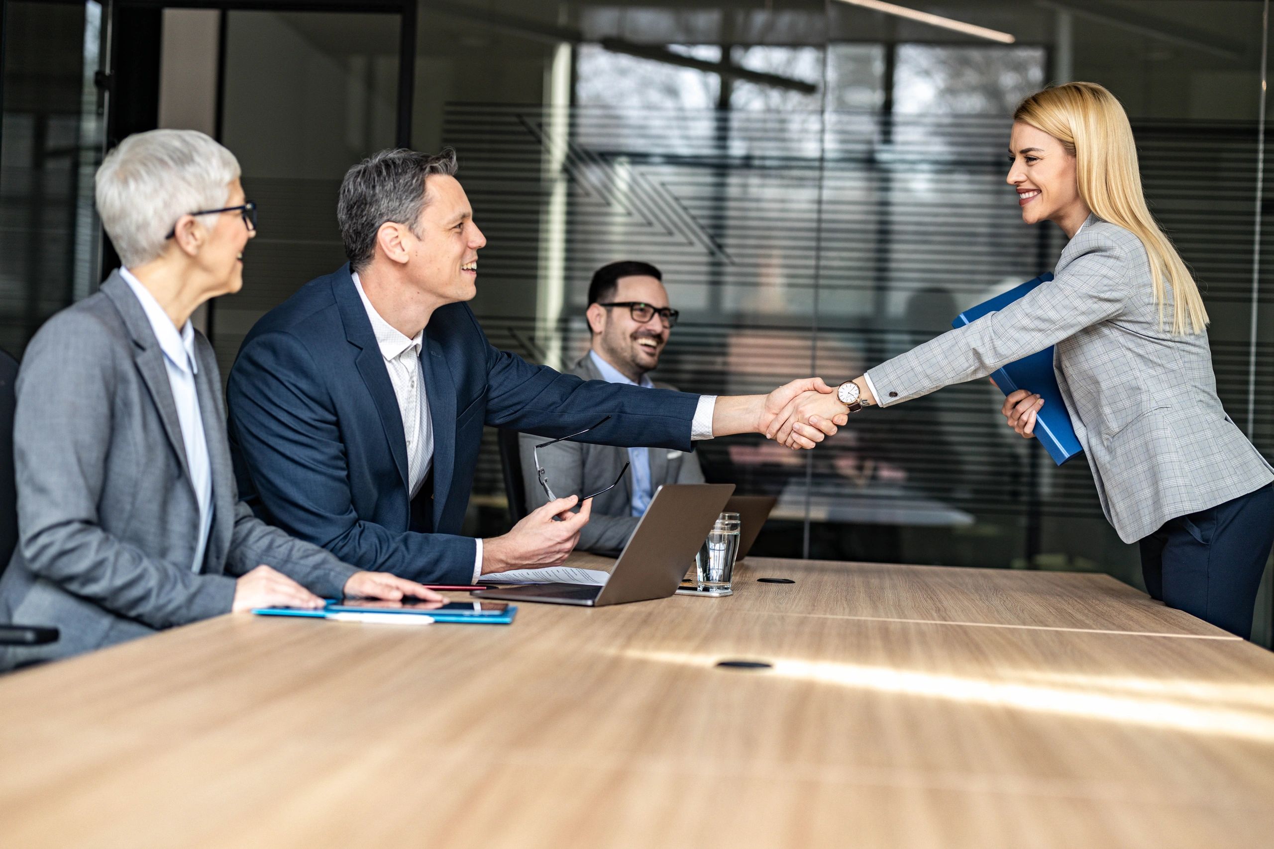 HR leader shaking hands with a candidate after a successful interview in a modern office